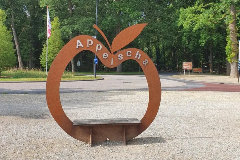 Cortenstalen kunstwerk in de vorm van een appel met de naam Appelscha en een bankje eronder