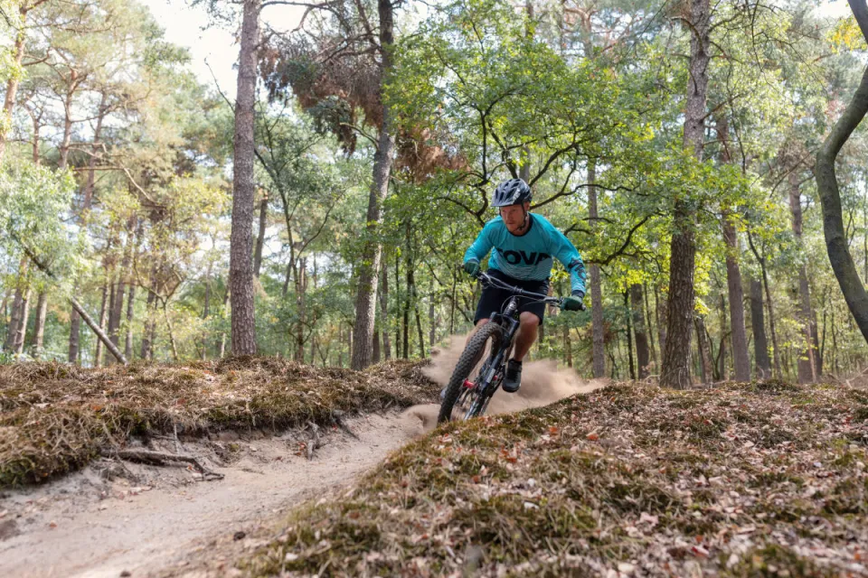 Mountainbiker rijdt over een smal bospad door het bos bij Appelscha