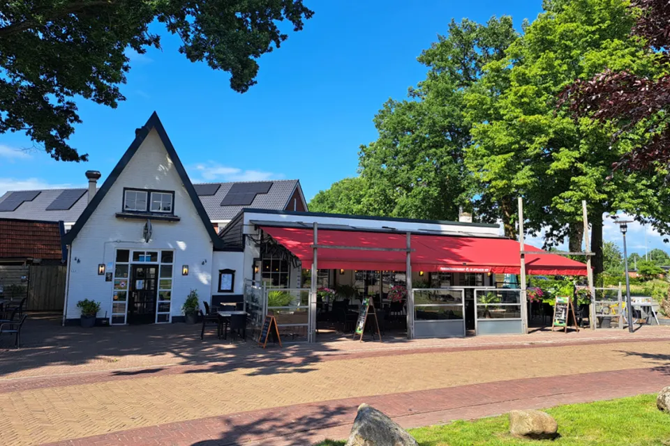 Wit horecapand met rode luifel en terras van De Appelsche Hof in Appelscha