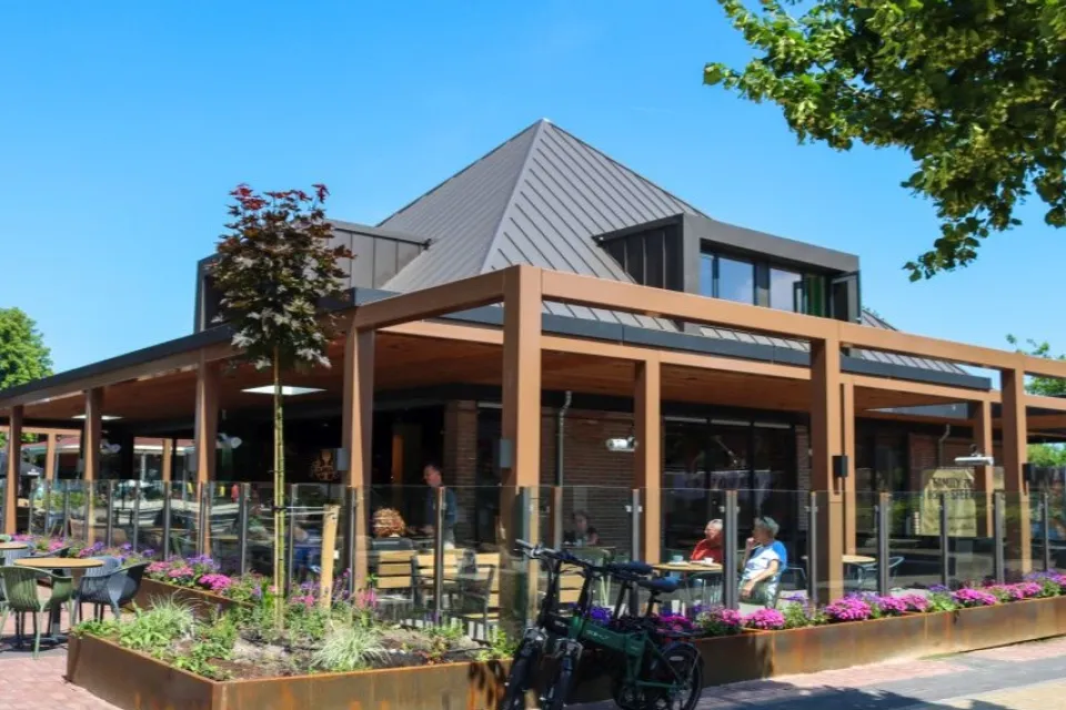 Modern restaurant met houten veranda, terras en bloembakken in Appelscha