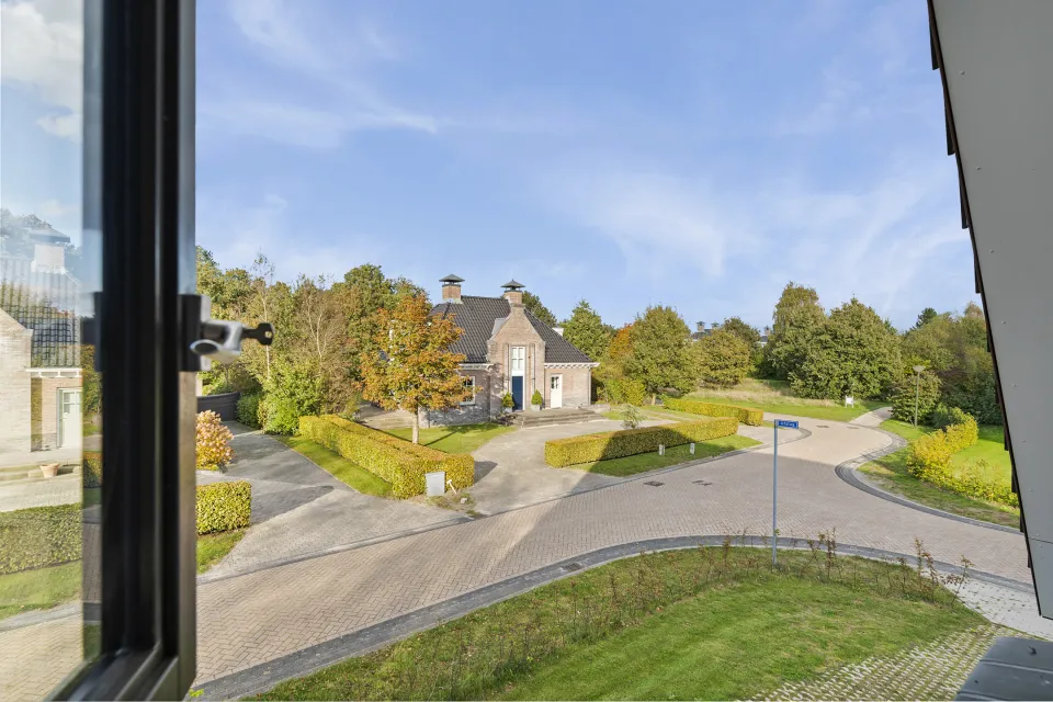 Uitzicht vanuit het raam van vakantiewoning Boszandoog aan Ofslag 2 op de laan van Buitenplaats de Hildenberg
