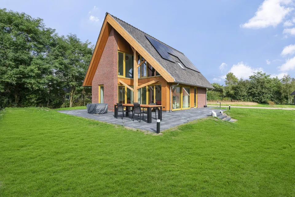 Vakantiewoning Calluna Wellness aan Ofslag 10 met puntdak en terras aan een groot grasveld op Buitenplaats de Hildenberg