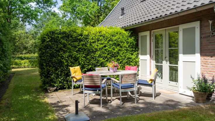 Terras met tuintafel en stoelen naast vakantiewoning Erebia aan Koele 9 op Buitenplaats de Hildenberg